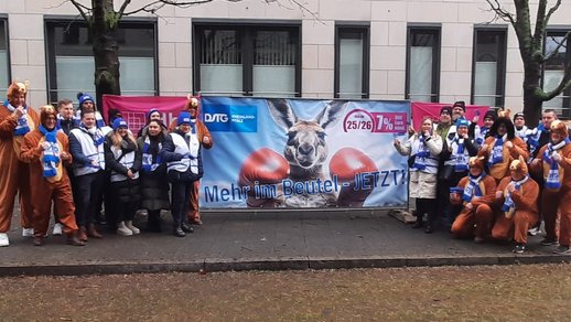 Gruppenbild vor Banner mit Känguru und Slogan "Mehr im Beutel - jetzt!"