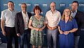 Gruppenbild mit vier Männern udn zwei Frauen vor einer dunkelblauen Logo-Wand