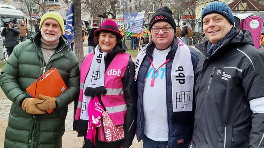 Personenquartett vor Demonstranten