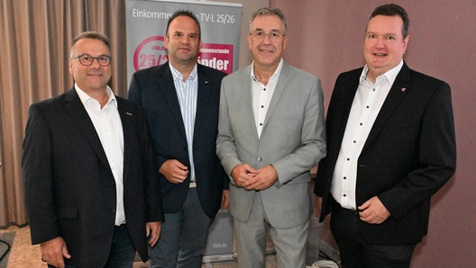 Gruppenbild mit vier Herren vor einem Kampagnen-Roll-Up