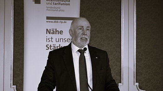 Ehemaliger dbb Bundesvorsitzender Ulrich Silberbach an einem Rednerpult vor einem Logo-Roll-Up