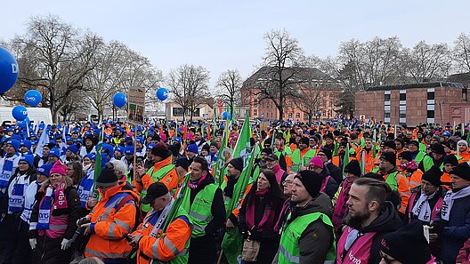 Große Menschenmenge mit FAhnen udn Bannern auf einem Platz.