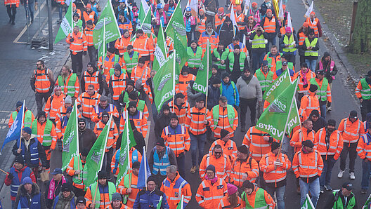 Demonstranten menge auf einer Straße, die meisten im Vordergrund tragen verkehrsgelbe Funktionskleidung