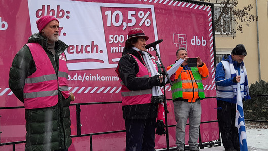 Rednerin auf einem Podium mit KAmpagnen-Banner