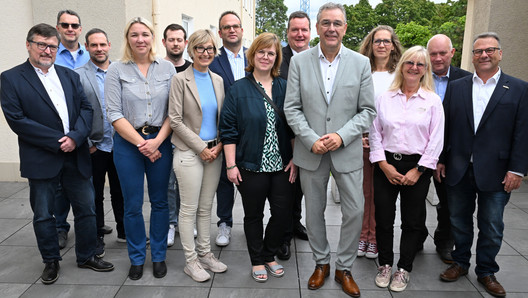 Gruppenbild mit 14 Personen auf einer Veranda.